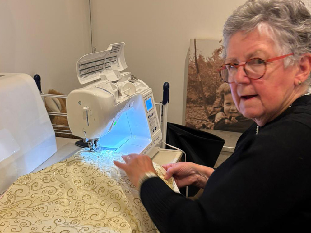 Joke werkt aan een naaimachine met roomwitte stof