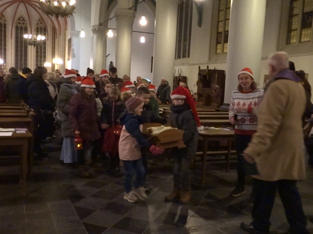 kinderen tillen de kribbe met kindeke Jezus de kerk uit naar de kerststal op de Haagsemarkt