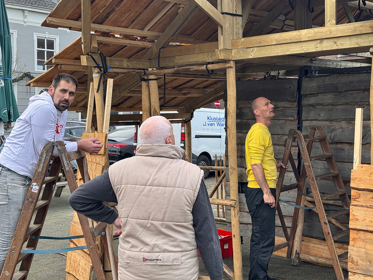 Bouwploeg van de kerststal kijkt naar het dak