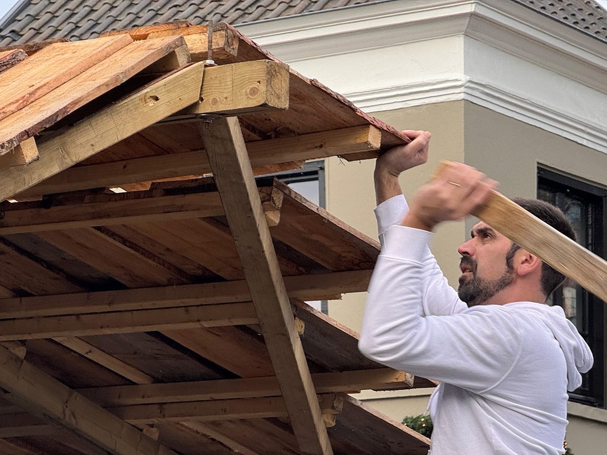Thomas slaat op een balk om het dak goed te plaatsen