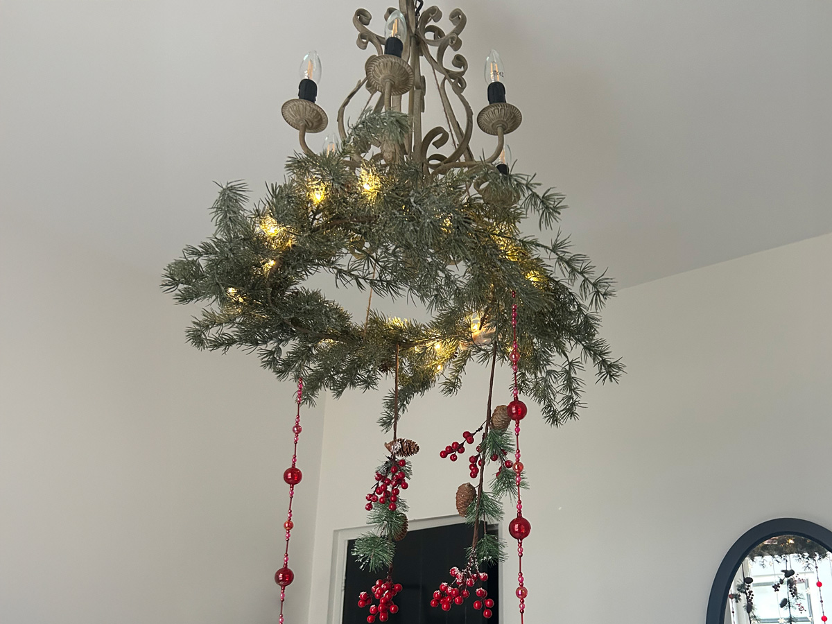 Aan het plafond een lamp met maretakken en rode versiering