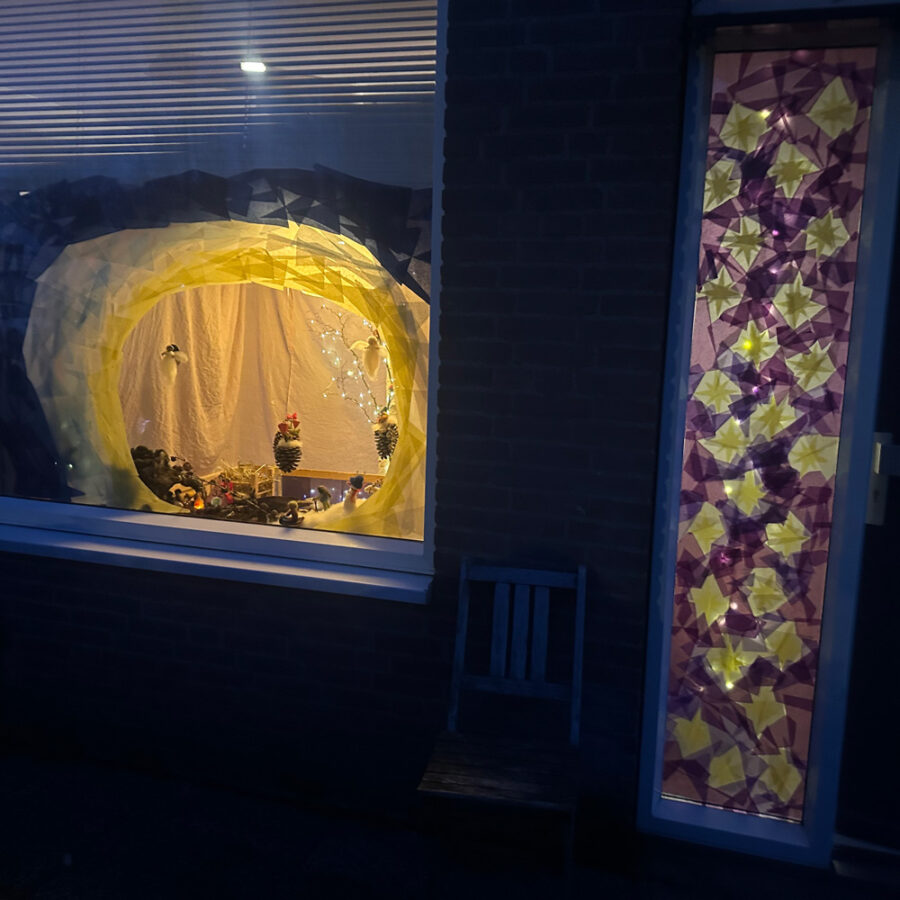 Een sfeervol verlicht tafereeltje achter een huiskamerraam