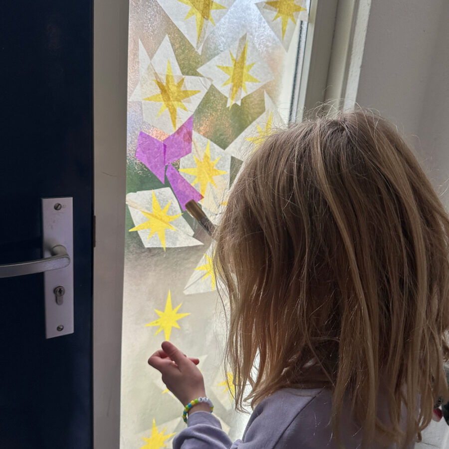 kindje kijkt naar de doorzichtige sterren geplakt op een raam van een deur