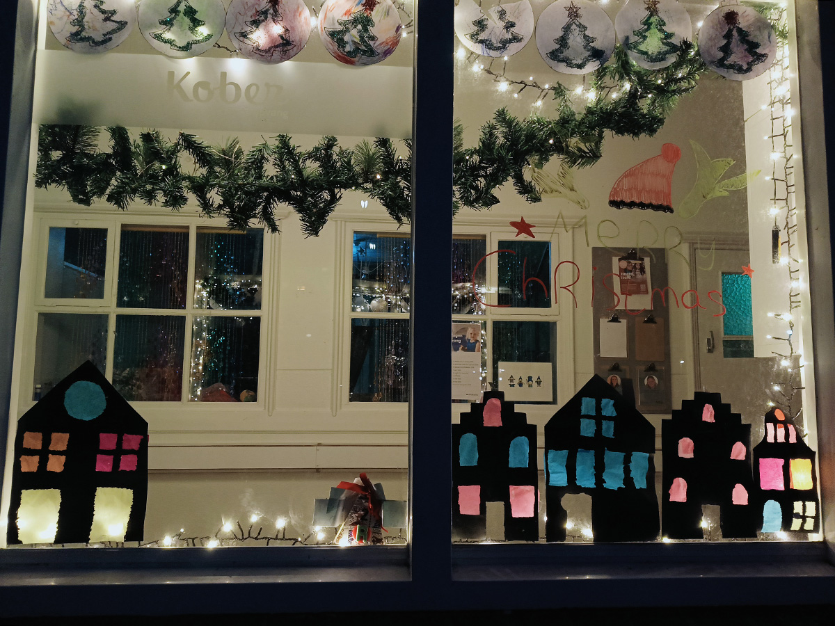 uit zwart papier geknipte huisjes met gekleurde ramen