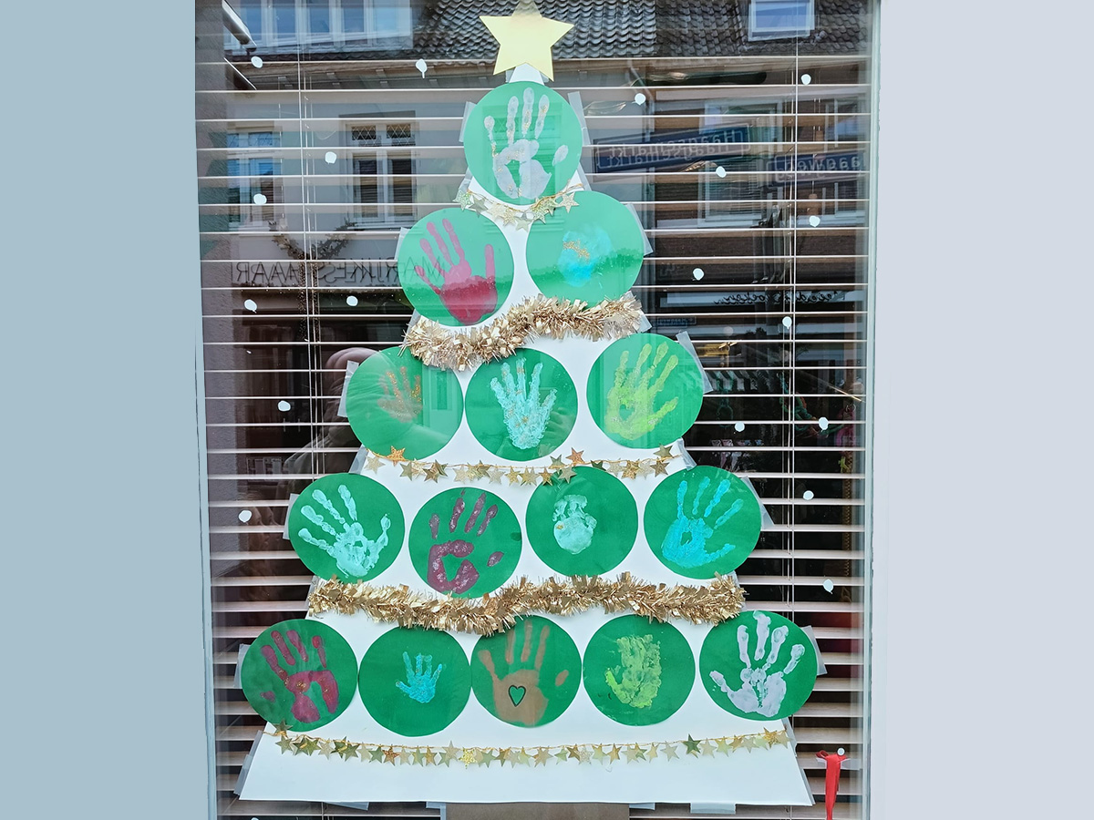 boom gemaakt van groene ronde velletjes met witte kinderhandsafdrukken