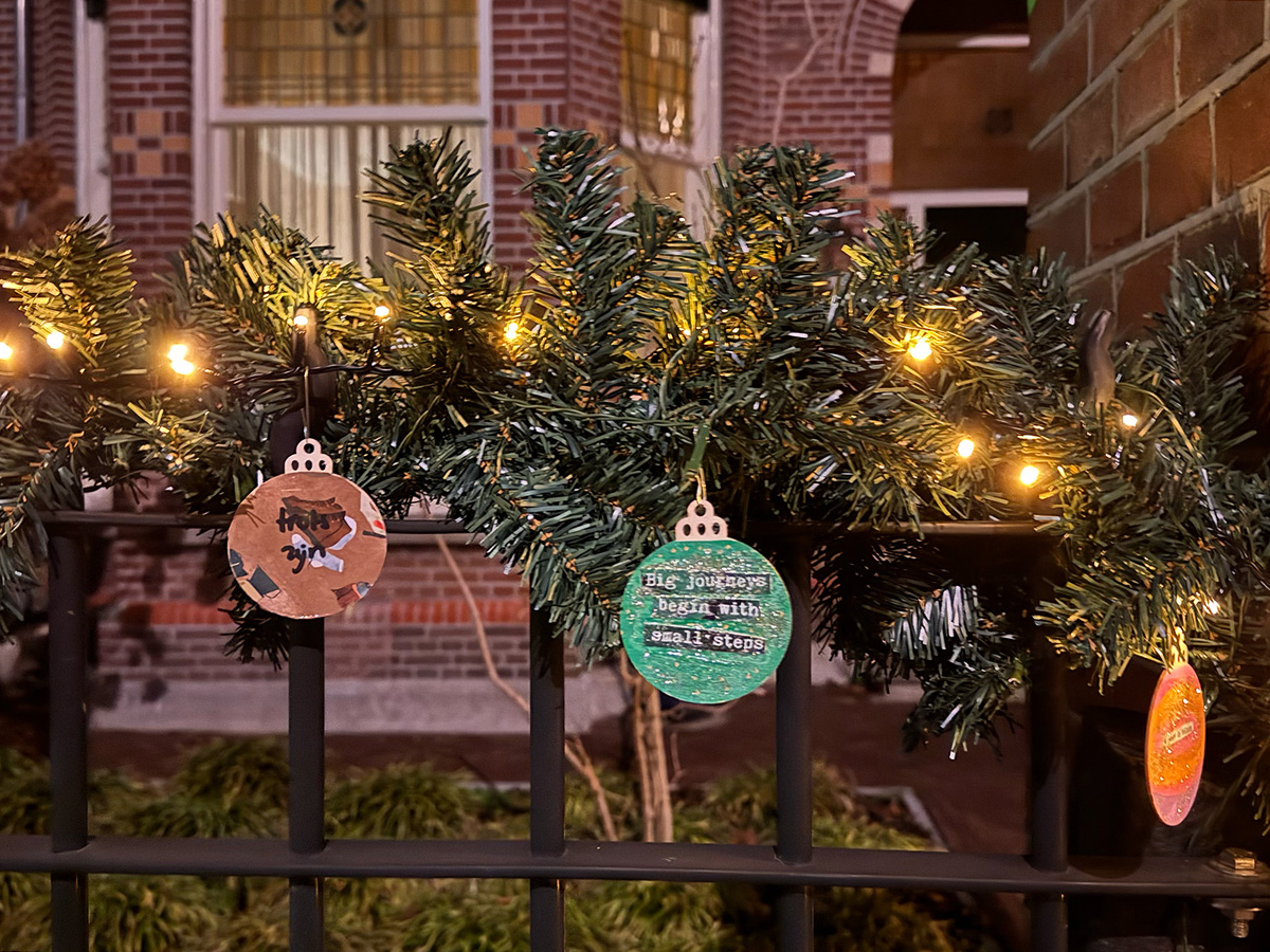 met papier gemaakte kerstballen met kerstboomtakken bevestigd aan een hek