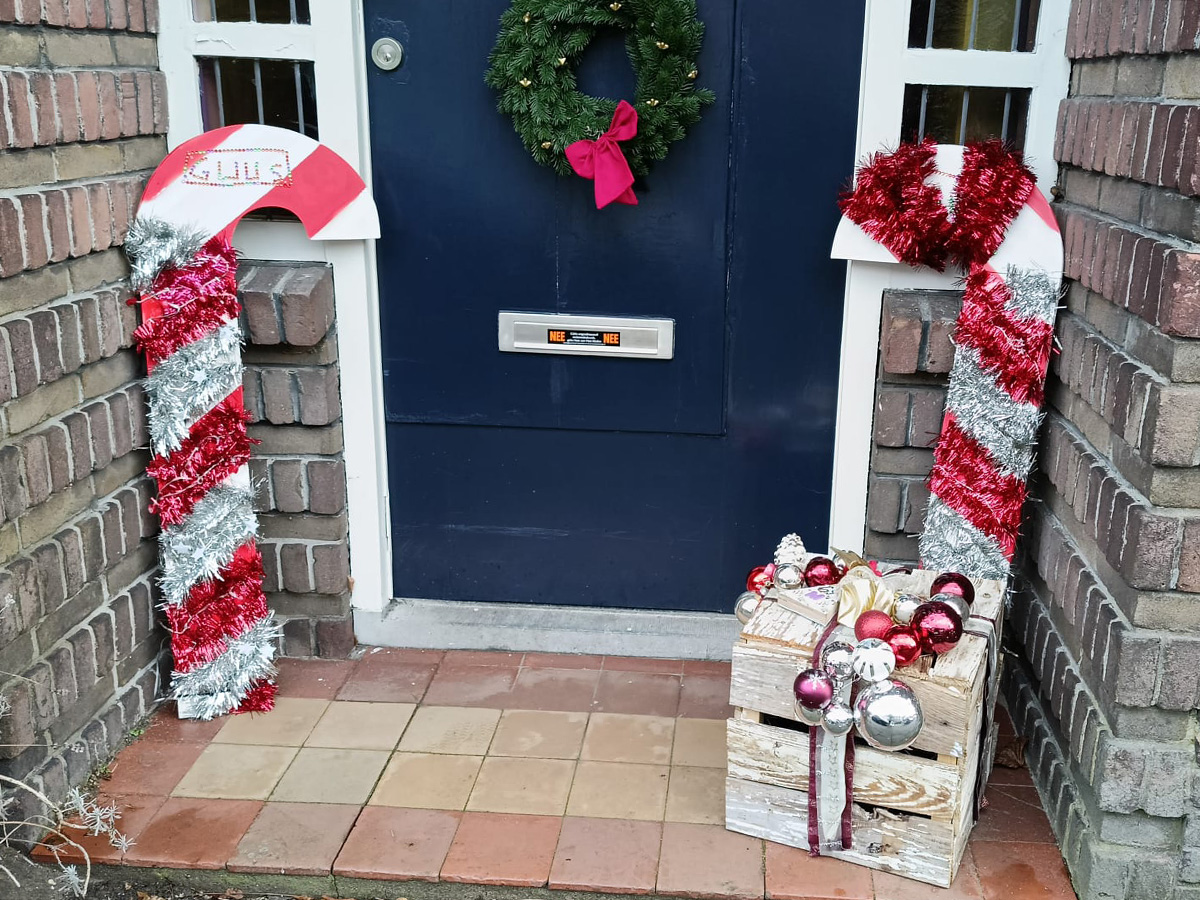 kerstdecoraties - een snoepstok en een cadeautje - naast een voordeur